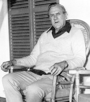 Foto do escritor australiano Patrick White sentado numa cadeira.