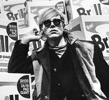 Foto de Andy Warhol em frente a uma de suas obras de arte