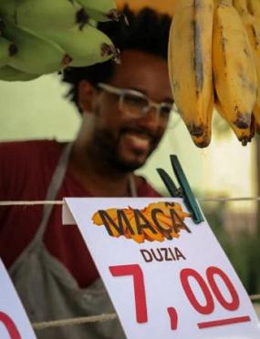 Feirante numa banca de bananas e maçãs