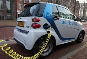 Foto de um carro el&eacute;trico sendo carregado com energia