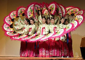 Foto de mulheres coreanas com trajes tradicionais fazendo um dan&ccedil;a com uso de leques