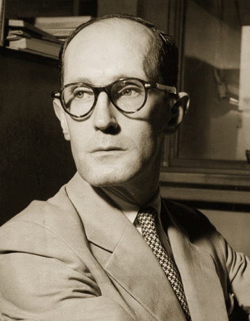 Foto de Carlos Drummond de Andrade. Homem de meia idade, de &oacute;culos preto e terno e gravata.