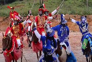 Foto da Cavalhada com cavaleiros de trajes azul e vermelho