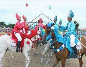 Cavalhada, cavaleiros fantasiados em azul e vermelho montados em cavalos.