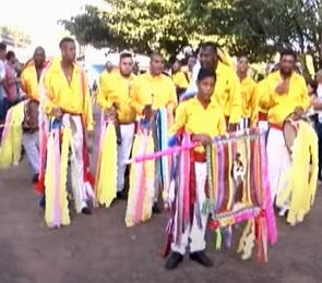 Homens vestidos com camisas amarelas participando da Congada