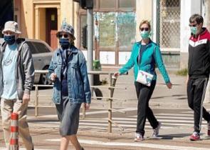 Pessoas de m&aacute;scaras andando numa rua