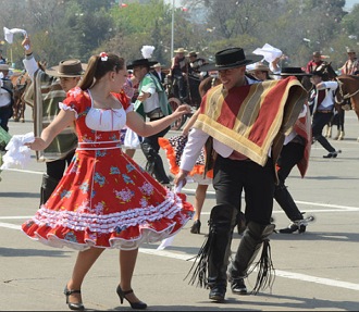 Um casal de chilenos dan&ccedil;ando numa comemora&ccedil;&atilde;o de rua. Eles est&atilde;o com trajes tradicionais do chile.