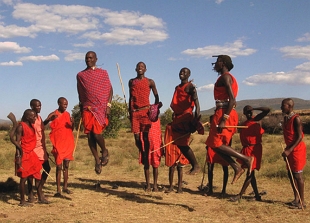 Integrantes da trivo massai, vestidos de vermelho, fazendo uma dan&ccedil;a que consiste em dar saltos
