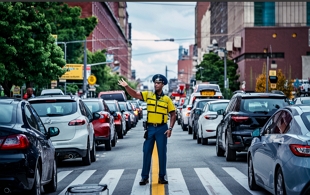Ilustra&ccedil;&atilde;o mostrando um agente de tr&acirc;nsito, orientando os motoristas numa rua.