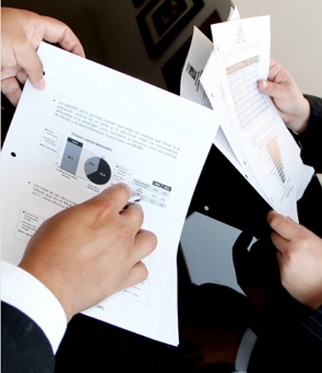 M&atilde;os de um economista mostrando gr&aacute;ficos para outra pessoa