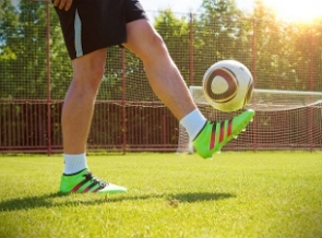 Parte de baixo do corpo de uma pessoa chutando uma bola