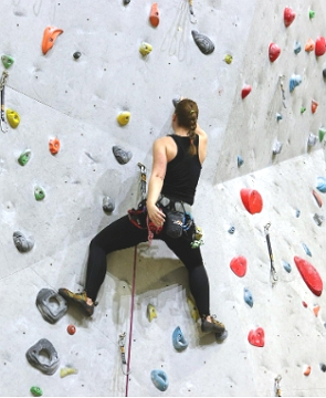 Escaladora subindo numa parede de escalada