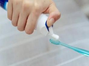 Foto mostrando uma mão colocando pasta numa escova de dente.