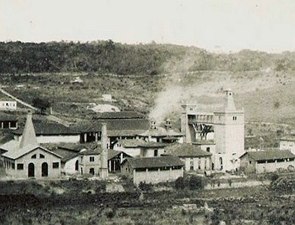 Foto em preto e branco de uma fábrica soltando fumaça