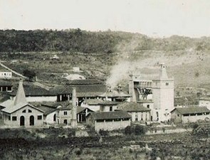Foto em preto e branco de uma fábrica soltando fumaça