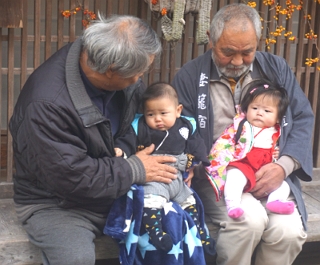 Foto mostrando dois idosos japoneses com seus netos