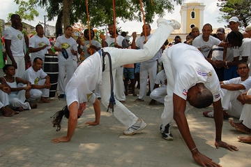 Pessoas vestidas de branco praticando capoeira