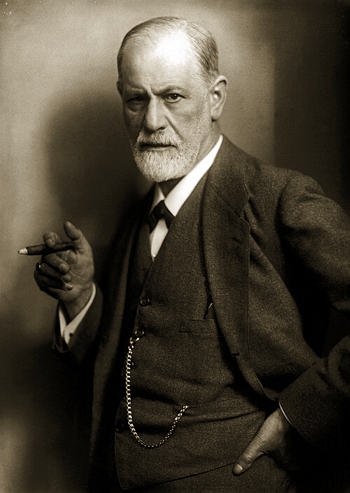 Foto de Freud, homem idoso de barba branca e calvo, segurando um charuto e vestindo terno e gravata.