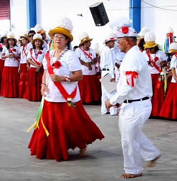 Homens e mulheres com roupas vermelha e branca fazendo uma dan&ccedil;a