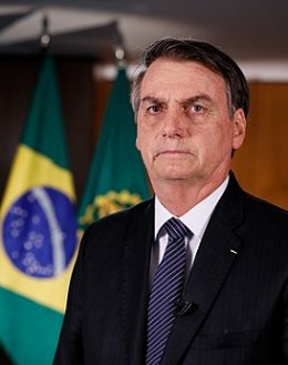 Foto do Presidente Jair Bolsonaro com bandeira do Brasil ao fundo