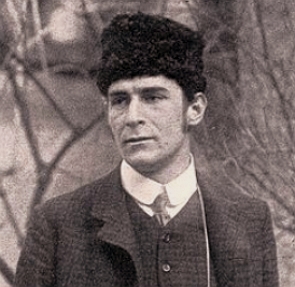 Foto em preto e branco de Franz Marc, homem de meia idade, branco, com chap&eacute;u preto na cabe&ccedil;a, num local com galhos secos de &aacute;rvores