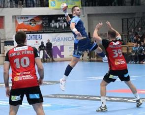 Foto de uma partida de Handebol com o jogador arremessando para o gol