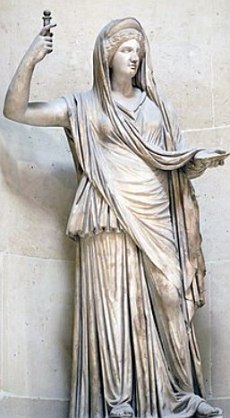 Estátua de uma mulher levantando o braço direito e com uma espécie de vestido.