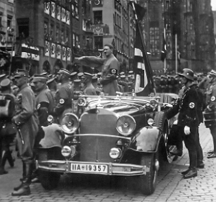 Hitler num carro aberto em desfile pelas ruas durante manifestação do partido Nazista