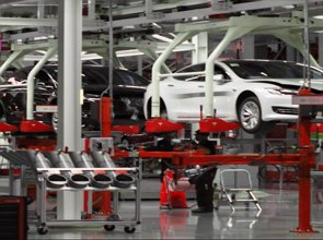 Foto de uma linha de produ&ccedil;&atilde;o de autom&oacute;veis mostrando um carro branco