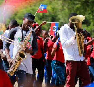 Haitianos tocando instrumentos musicais de sopro numa festa de rua