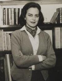 Lygia Fagundes Telles, escritora brasileira, em p&eacute; de bra&ccedil;os cruzados em frente uma estante de livros