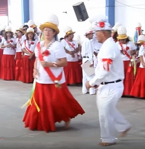 Homens e mulheres com roupas vermelha e branca fazendo uma dança