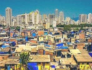 Foto de uma cidade com prédios ao fundo e casas populares na frente