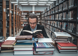 Imagem de um homem lendo um livro numa biblioteca
