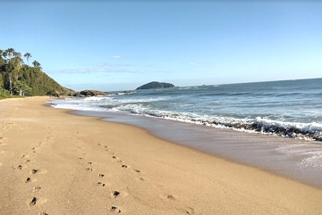Praia mostrando areia, ondas e montanhas ao fundo