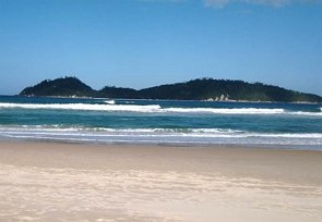 Praia mostrando areia, ondas e montanhas ao fundo