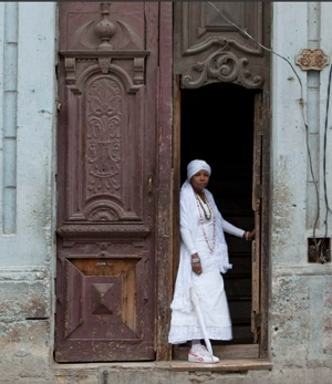 Foto de uma mulher praticante da Santer&iacute;a em frente a uma casa religiosa