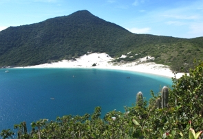 Foto de uma paisagem com montanhas e uma praia com mar e areia