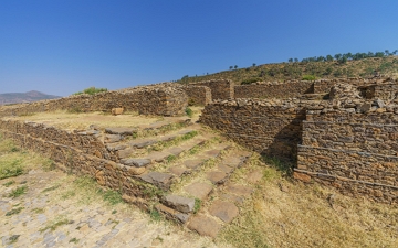 Foto mostrando escadas e paredes pela metade, feitas de pedra.