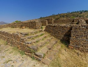 Foto mostrando escadas e paredes pela metade, feitas de pedra.