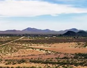 Paisagem de uma região com pouca vegetação e montanhas ao fundo