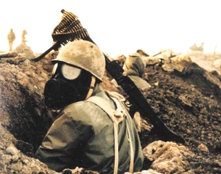 Foto de um soldado iraquiano, usando m&aacute;scara anti-g&aacute;s, numa trincheira.