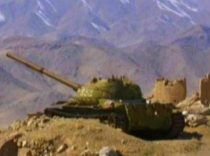 Foto de um tanque de guerra de cor verde escura num local com montanhas