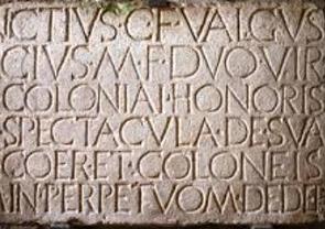 Texto em latim escrito em uma parede ou placo de argila