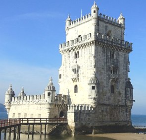 Foto de uma torre de cor cinza claro no formato quadrado com céu azul ao fundo