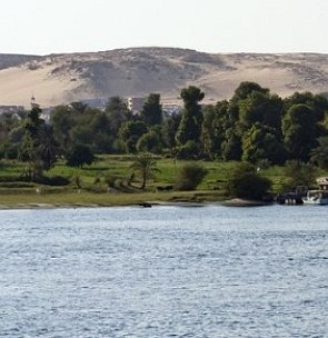 Foto com montanhas ao fundo, árvores e rio na parte inferior