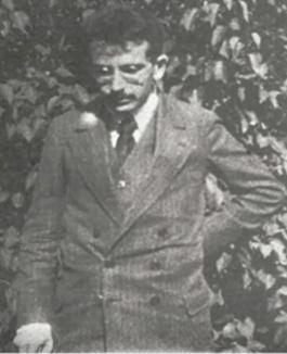 Foto de Walter Benjamin em pé e olhando para baixo.